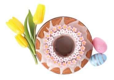Festively decorated Easter cake, painted eggs and yellow tulips on white background, top view
