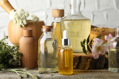 Photo of Aromatherapy. Different essential oils, herbs and flowers on wooden table