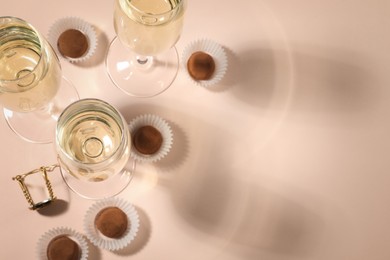 Photo of Glassesdelicious sparkling wine and chocolate truffles on pale pink background, above view. Space for text