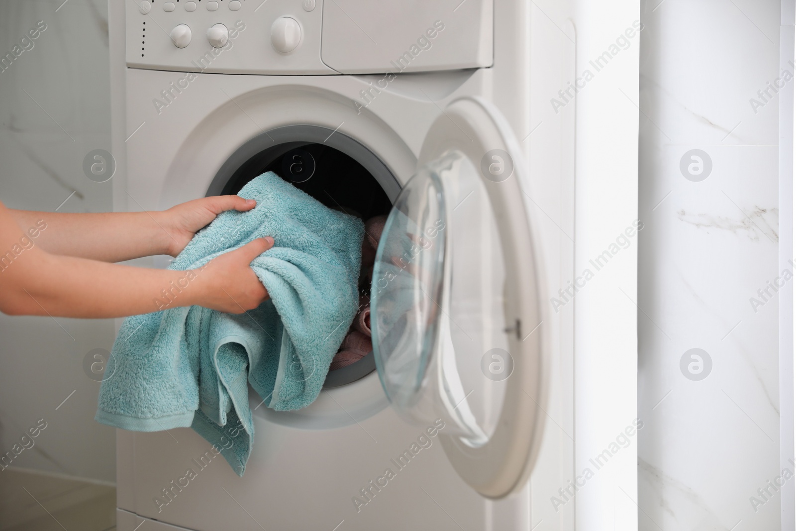 Photo of Woman putting dirty laundry into washing machine indoors, closeup