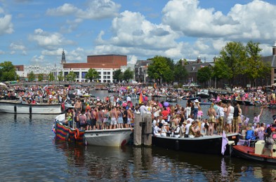 Photo of AMSTERDAM, NETHERLANDS - AUGUST 06, 2022: Many people in boats at LGBT pride parade on river