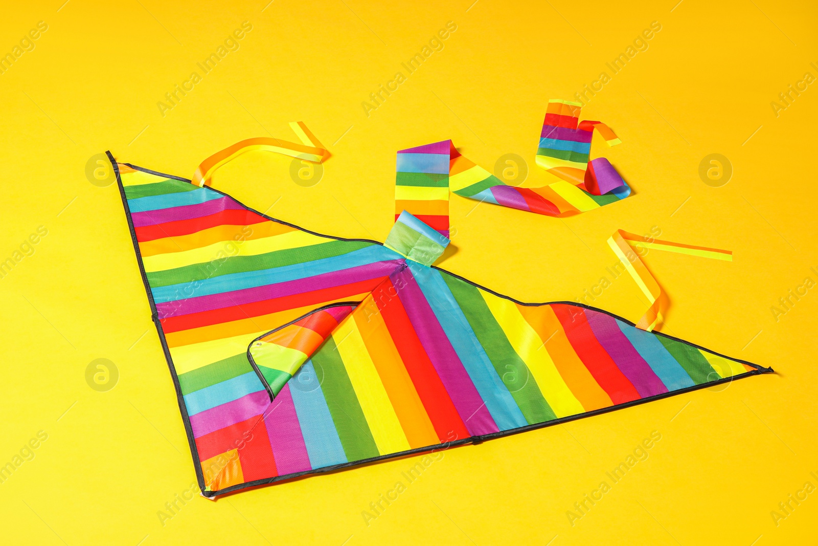 Photo of Beautiful bright rainbow kite on yellow background