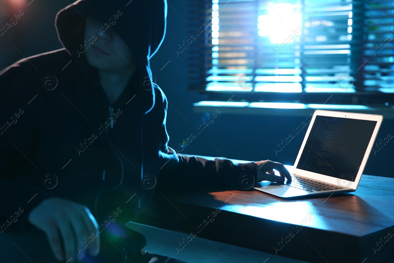 Photo of Hacker with laptop in dark room. Cyber crime