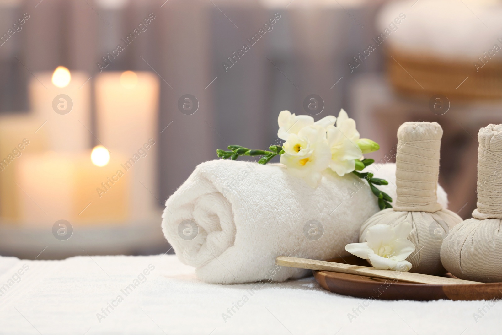 Photo of Beautiful composition with different spa products and flowers on white towel against blurred background. Space for text