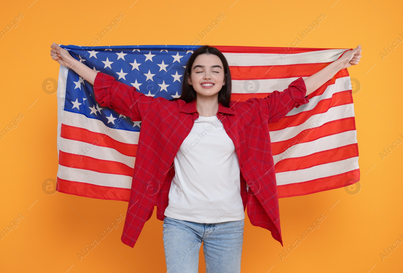 Photo of 4th of July - Independence Day of USA. Happy girl with American flag on yellow background