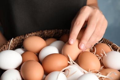 Photo of Woman with basket full of raw chicken eggs, closeup