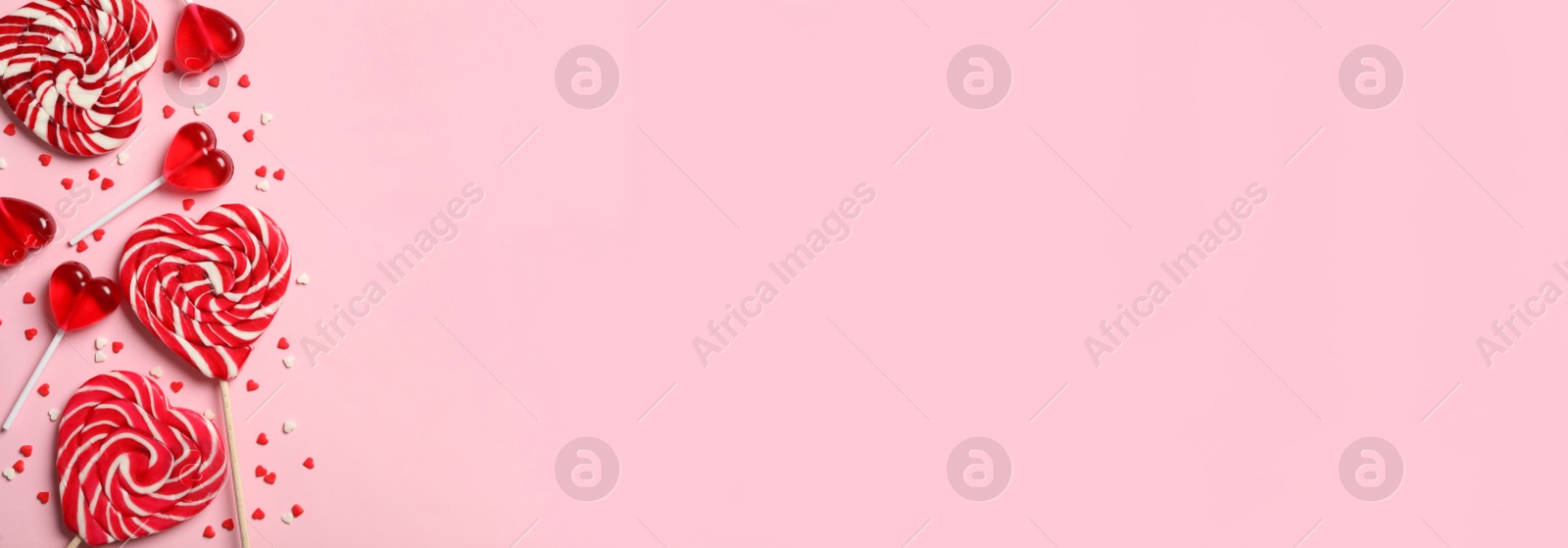 Image of Sweet heart shaped lollipops and sprinkles on pink background, flat lay with space for text. Valentine's Day banner design