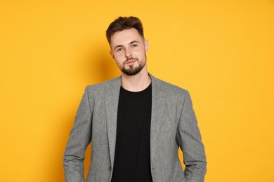 Photo of Handsome man in stylish grey jacket on yellow background