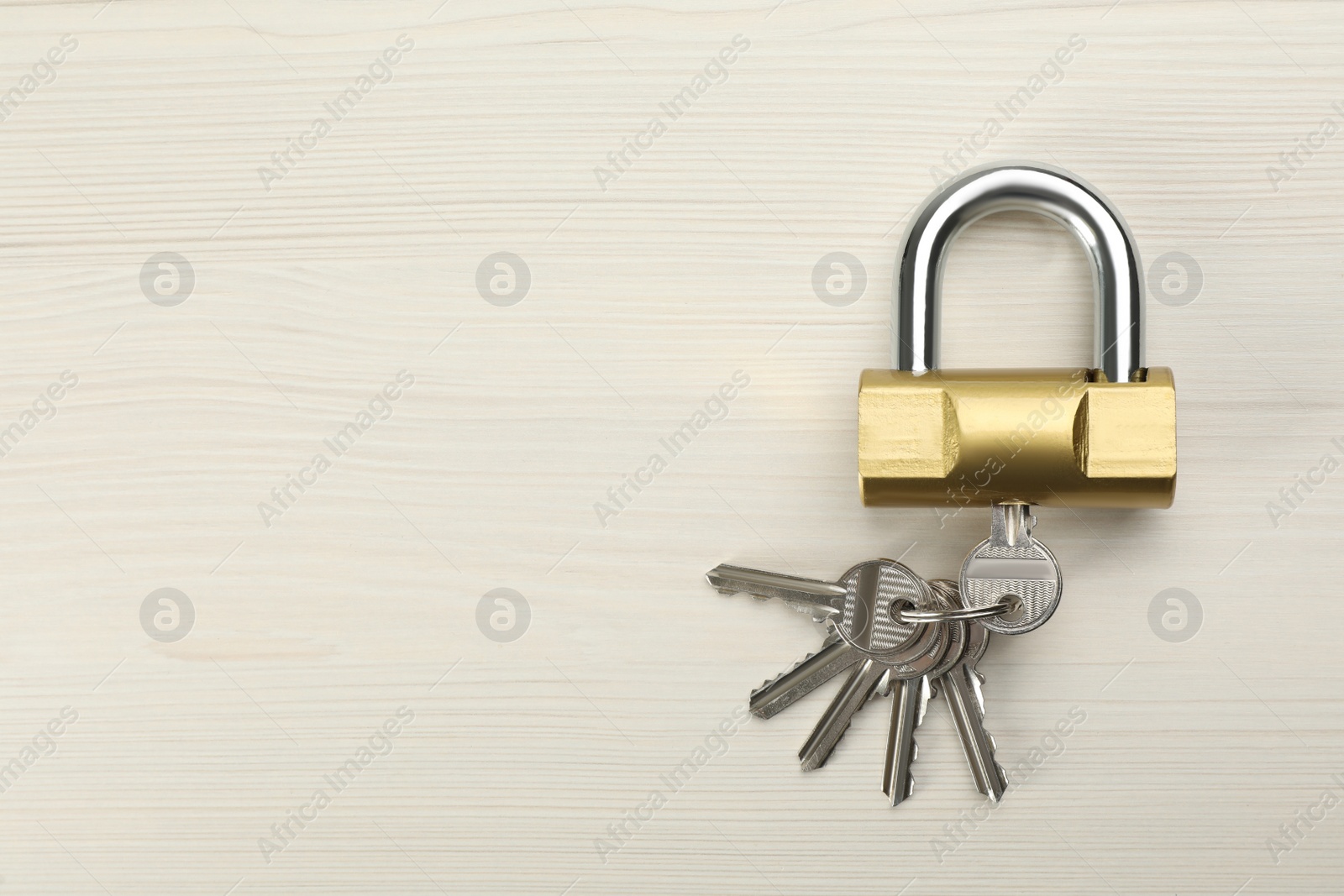 Photo of Modern padlock with keys on white wooden table, top view. Space for text