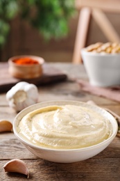 Photo of Delicious creamy hummus in dish on wooden table