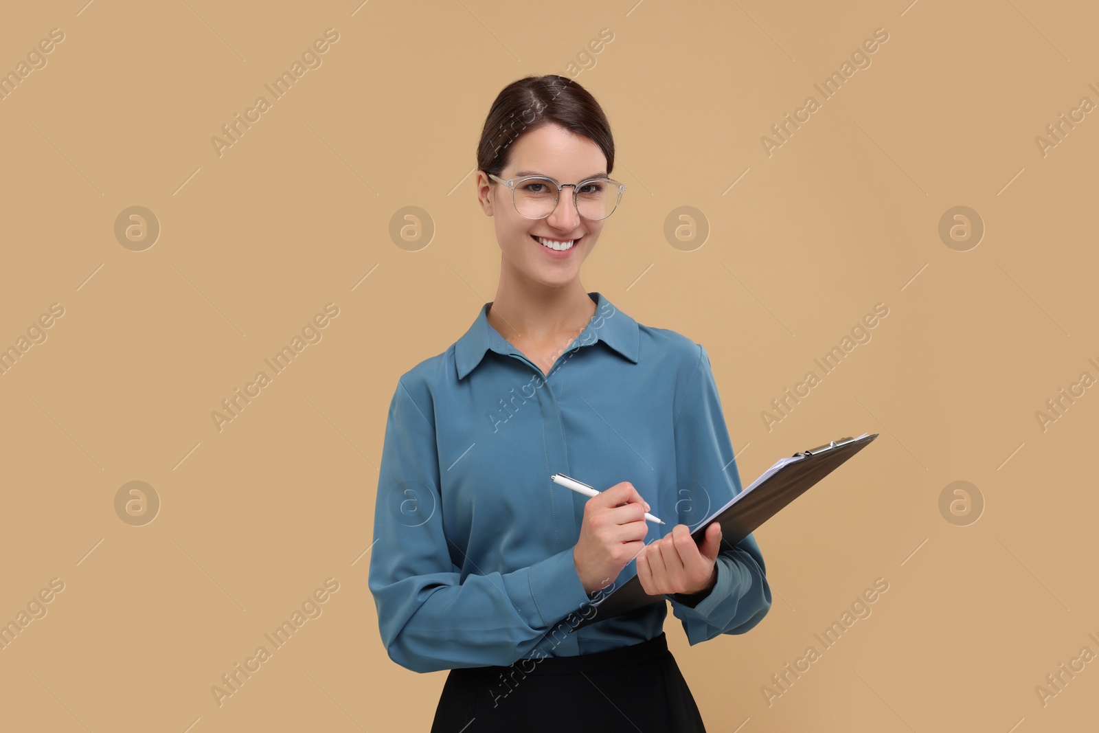 Photo of Happy secretary with clipboard and pen on beige background