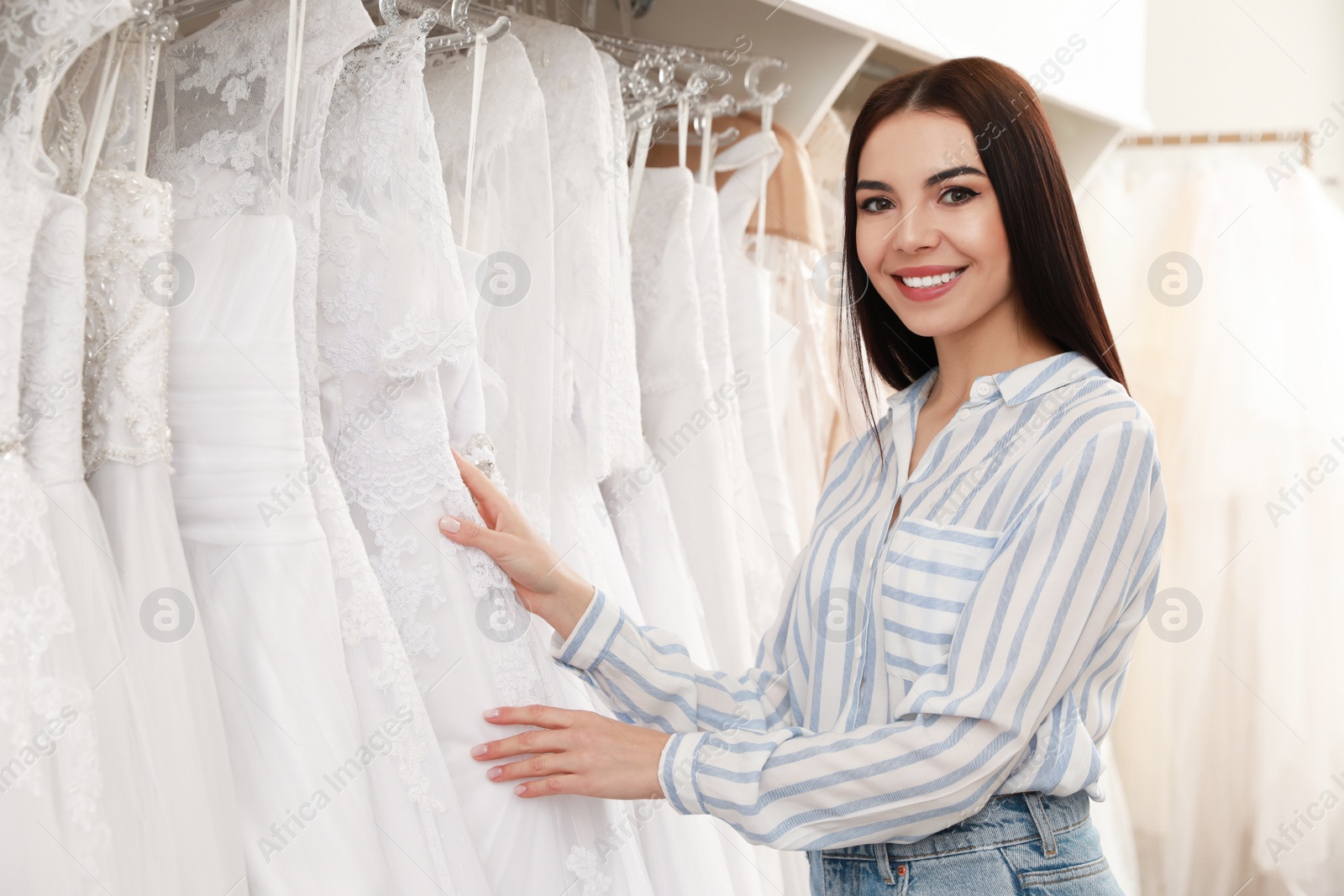 Photo of Young woman choosing wedding dress in salon