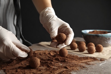 Photo of Woman preparing tasty chocolate truffles at table, closeup
