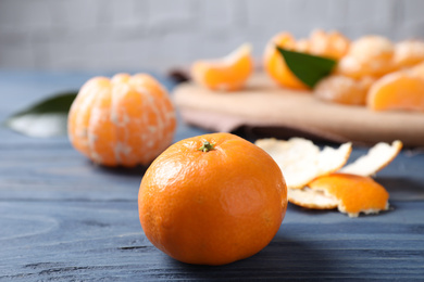 Photo of Fresh ripe tangerine on blue wooden table