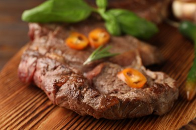 Delicious fried beef meat with chili pepper on wooden board, closeup