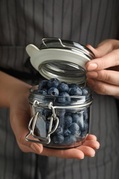 Photo of Woman holding jar with juicy fresh blueberries, closeup