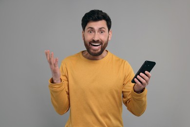 Photo of Emotional man with smartphone on grey background