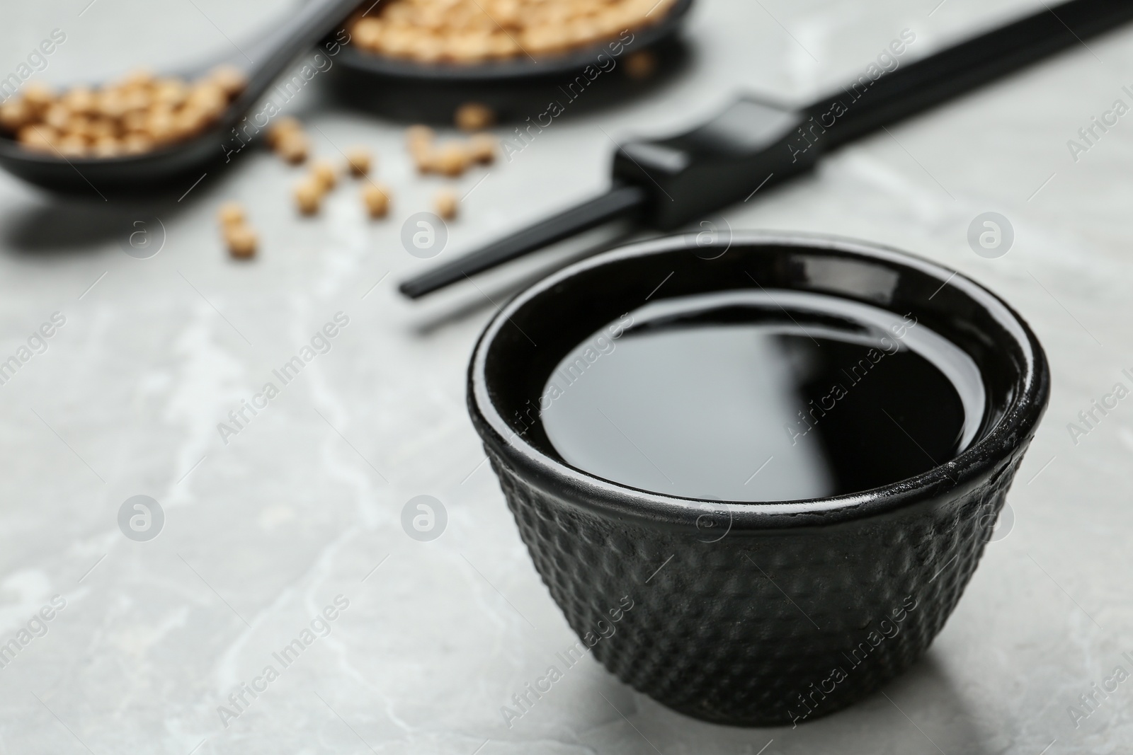 Photo of Bowl of soy sauce on grey table, closeup. Space for text