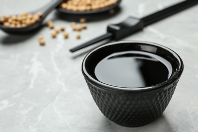 Bowl of soy sauce on grey table, closeup. Space for text