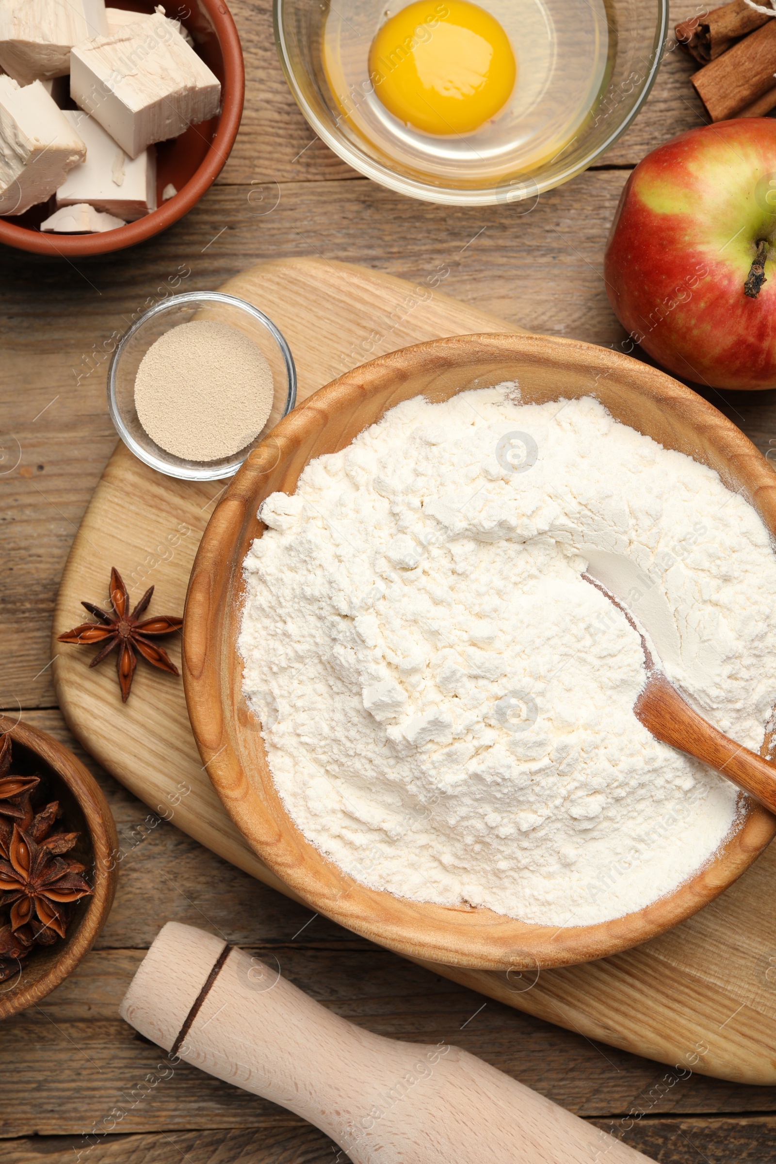 Photo of Flat lay composition with flour, rolling pin and ingredients on wooden table. Cooking yeast cake