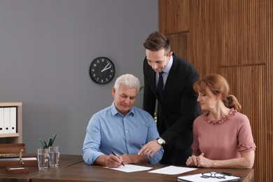 Young lawyer consulting senior couple in office