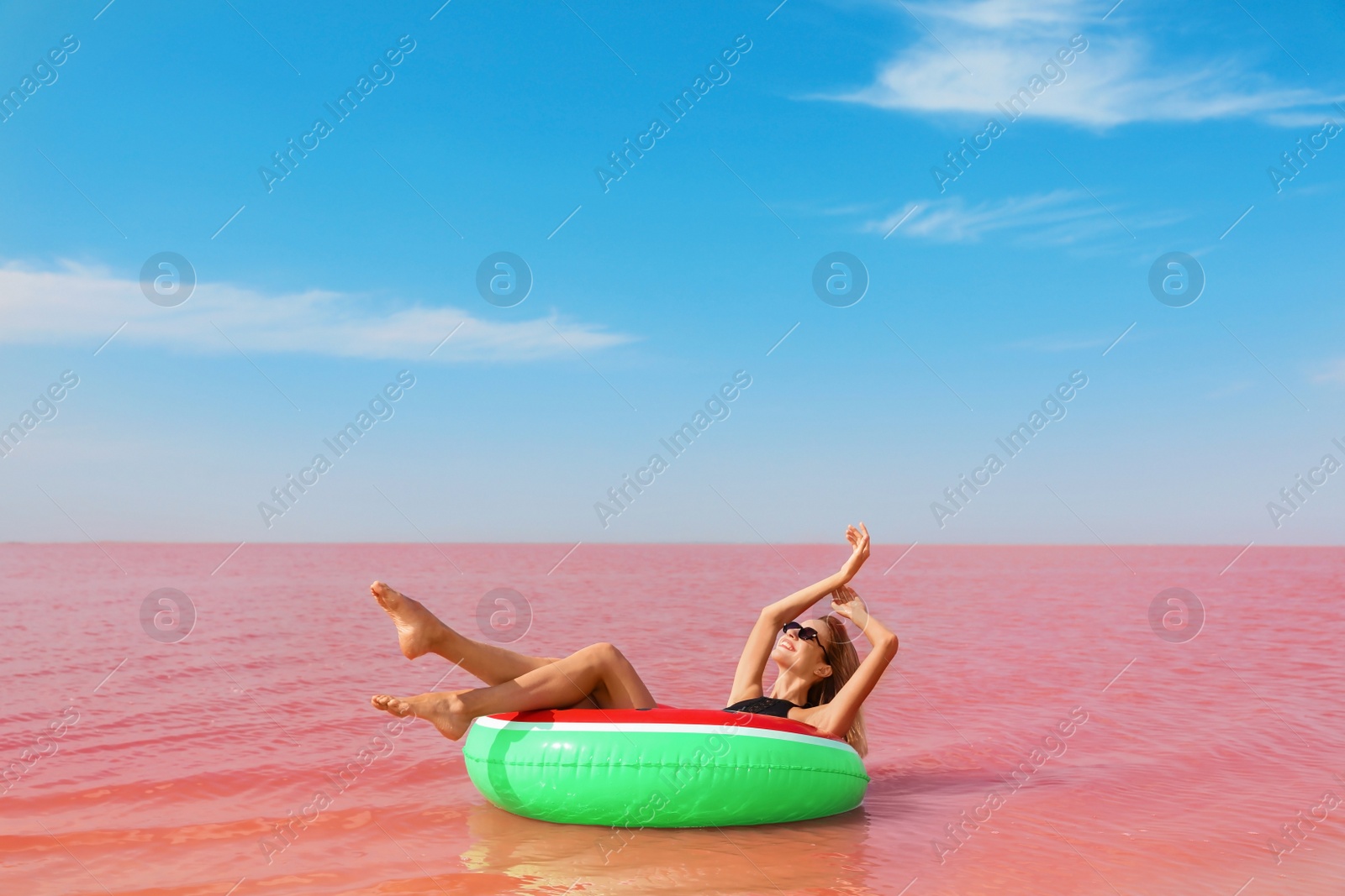 Photo of Beautiful woman on inflatable ring in pink lake