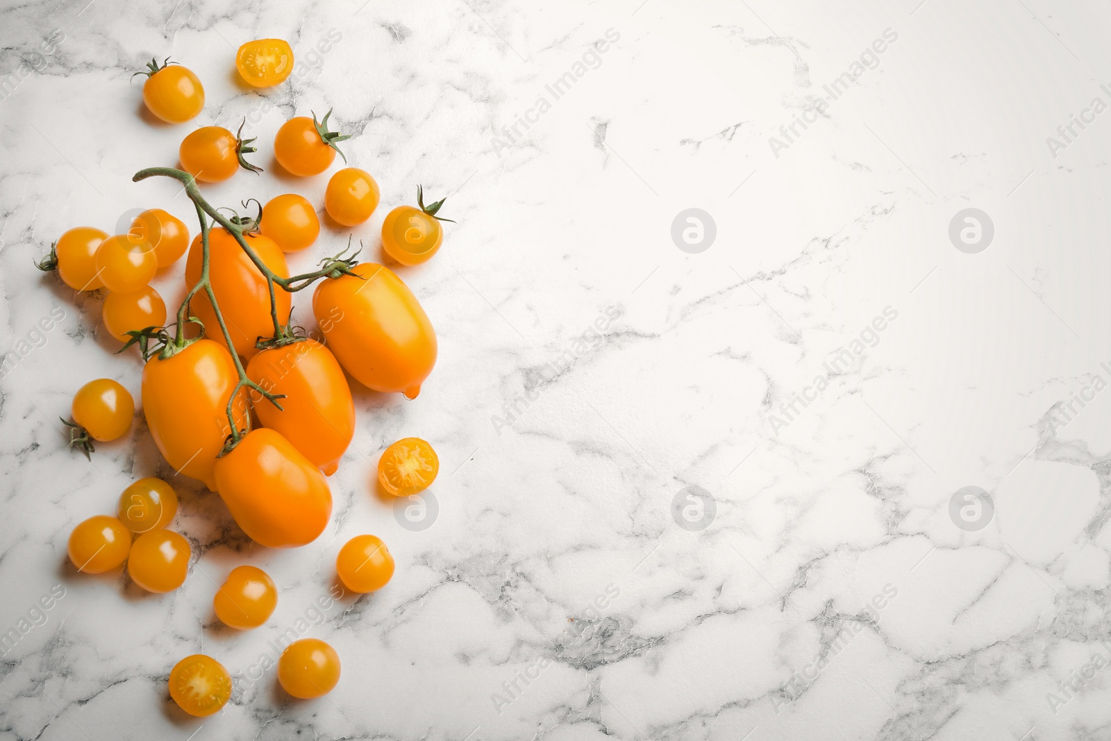 Photo of Ripe yellow tomatoes on white marble table, flat lay. Space for text