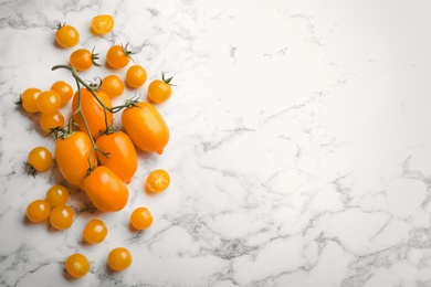 Photo of Ripe yellow tomatoes on white marble table, flat lay. Space for text