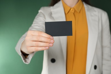 Woman holding black business card on green background, closeup