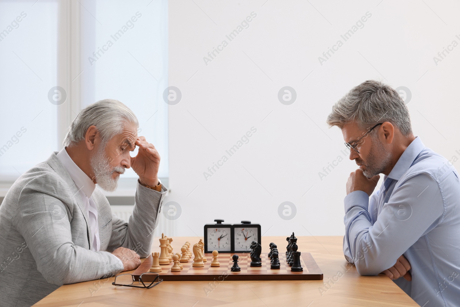 Photo of Men playing chess during tournament at table indoors