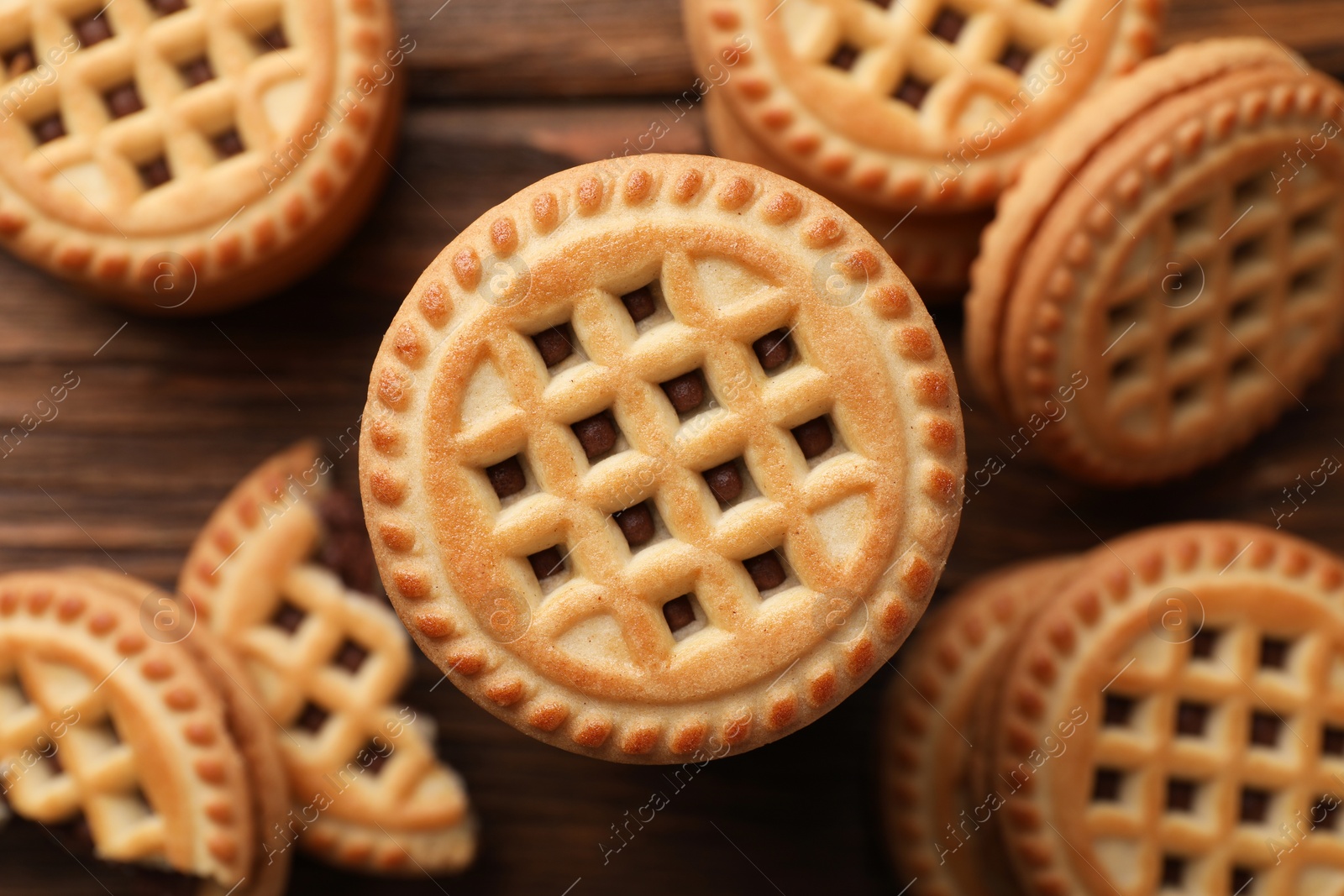 Photo of Tasty sandwich cookies with cream on wooden table, flat lay