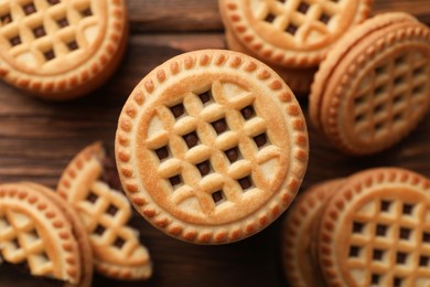 Photo of Tasty sandwich cookies with cream on wooden table, flat lay