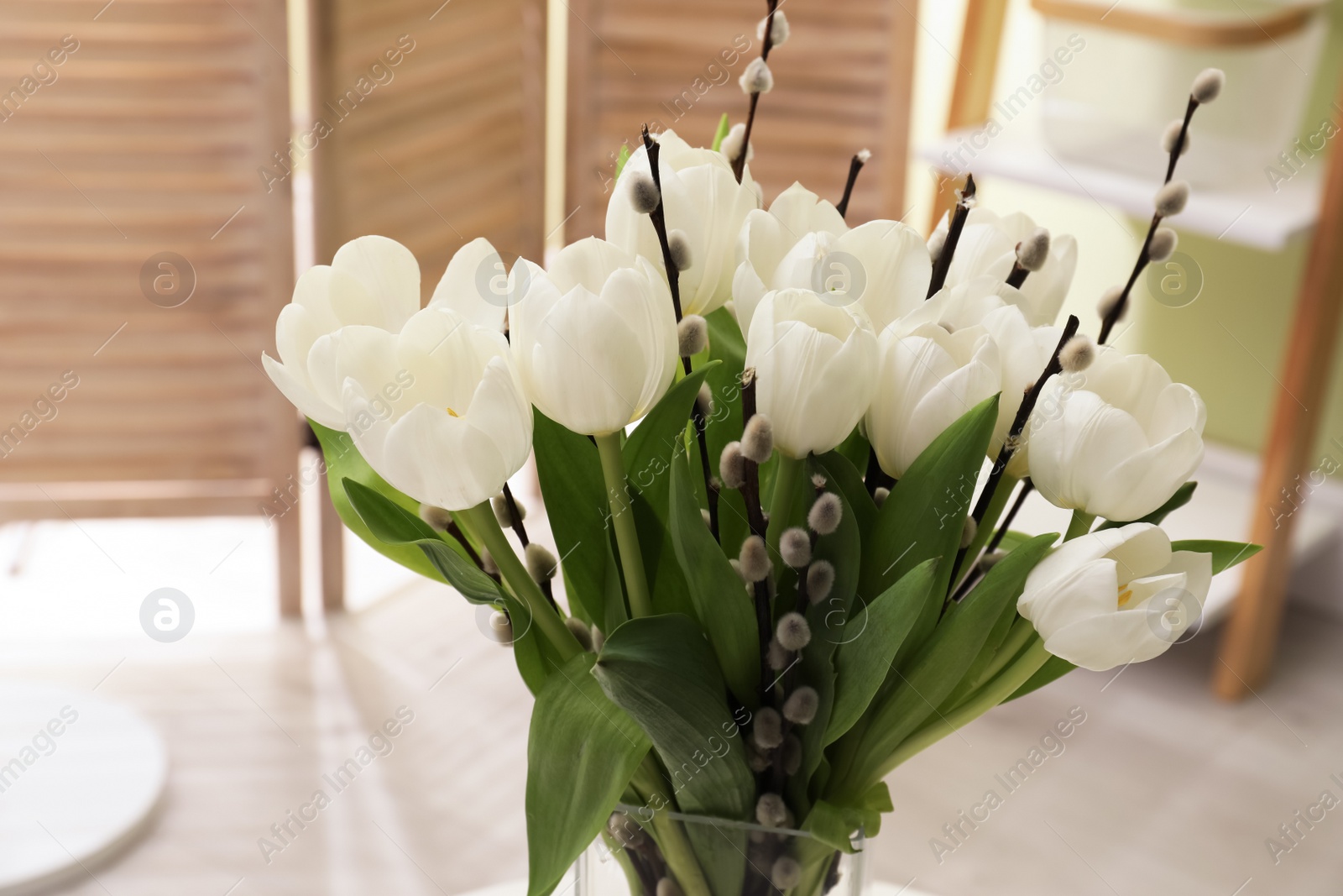 Photo of Beautiful bouquet of willow branches and tulips in vase indoors