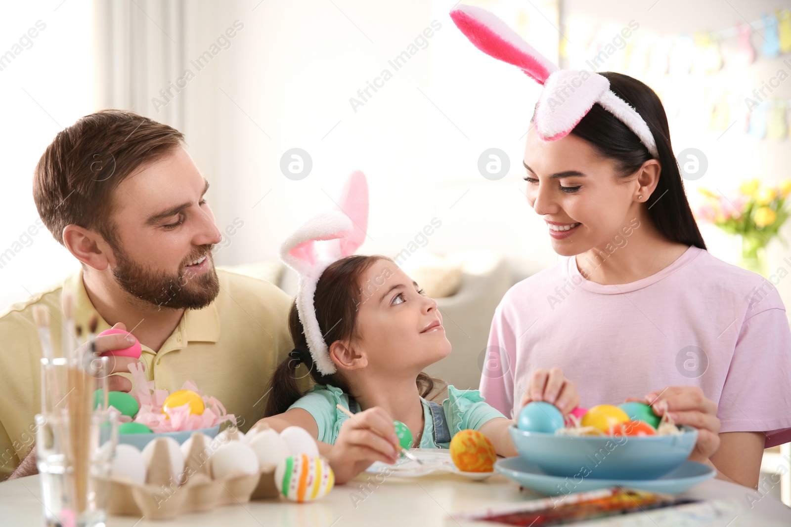 Photo of Happy family painting Easter eggs at table indoors