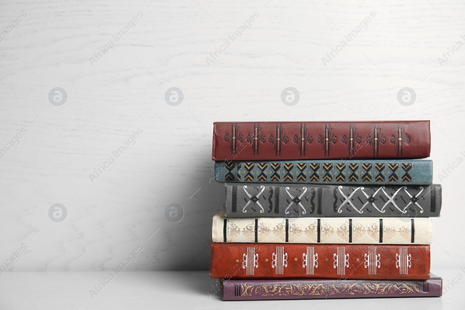 Photo of Collection of different books on table against white wooden background. Space for text