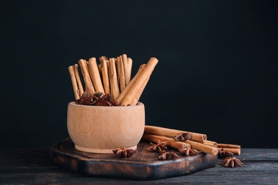 Photo of Aromatic cinnamon sticks and anise on black wooden table