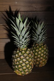 Photo of Two whole ripe pineapples on wooden table