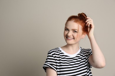 Candid portrait of happy red haired woman with charming smile on beige background, space for text