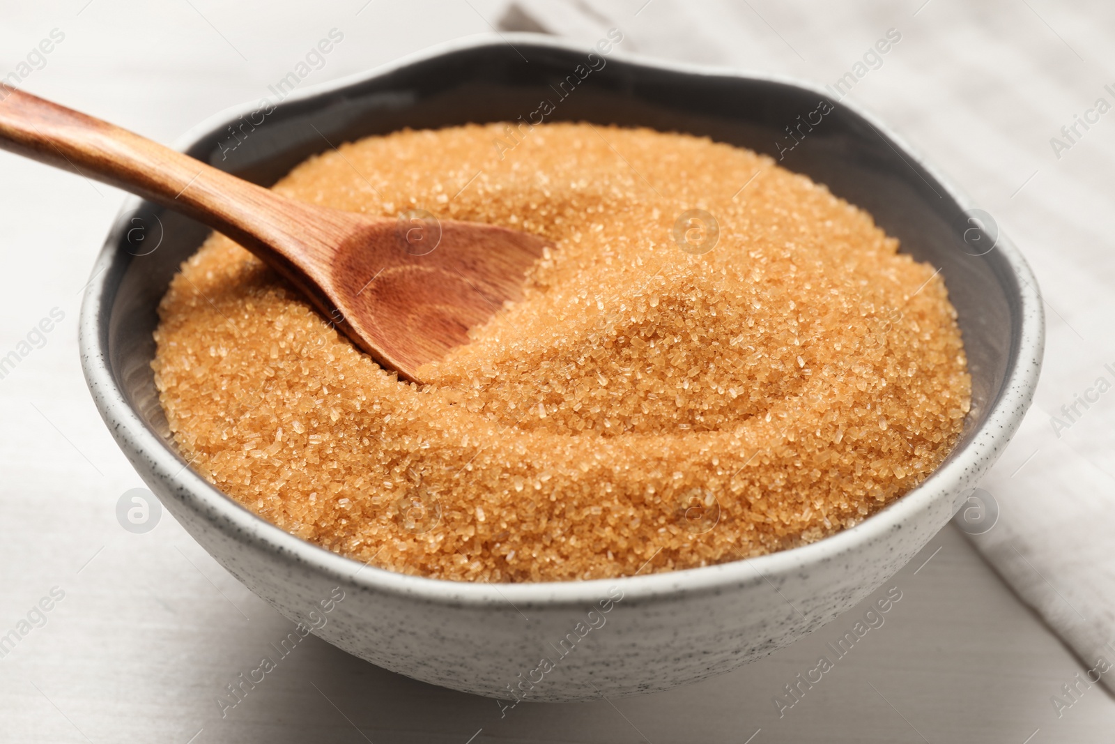 Photo of Brown sugar in bowl on white wooden table, closeup