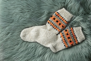Photo of Knitted socks on grey faux fur, flat lay