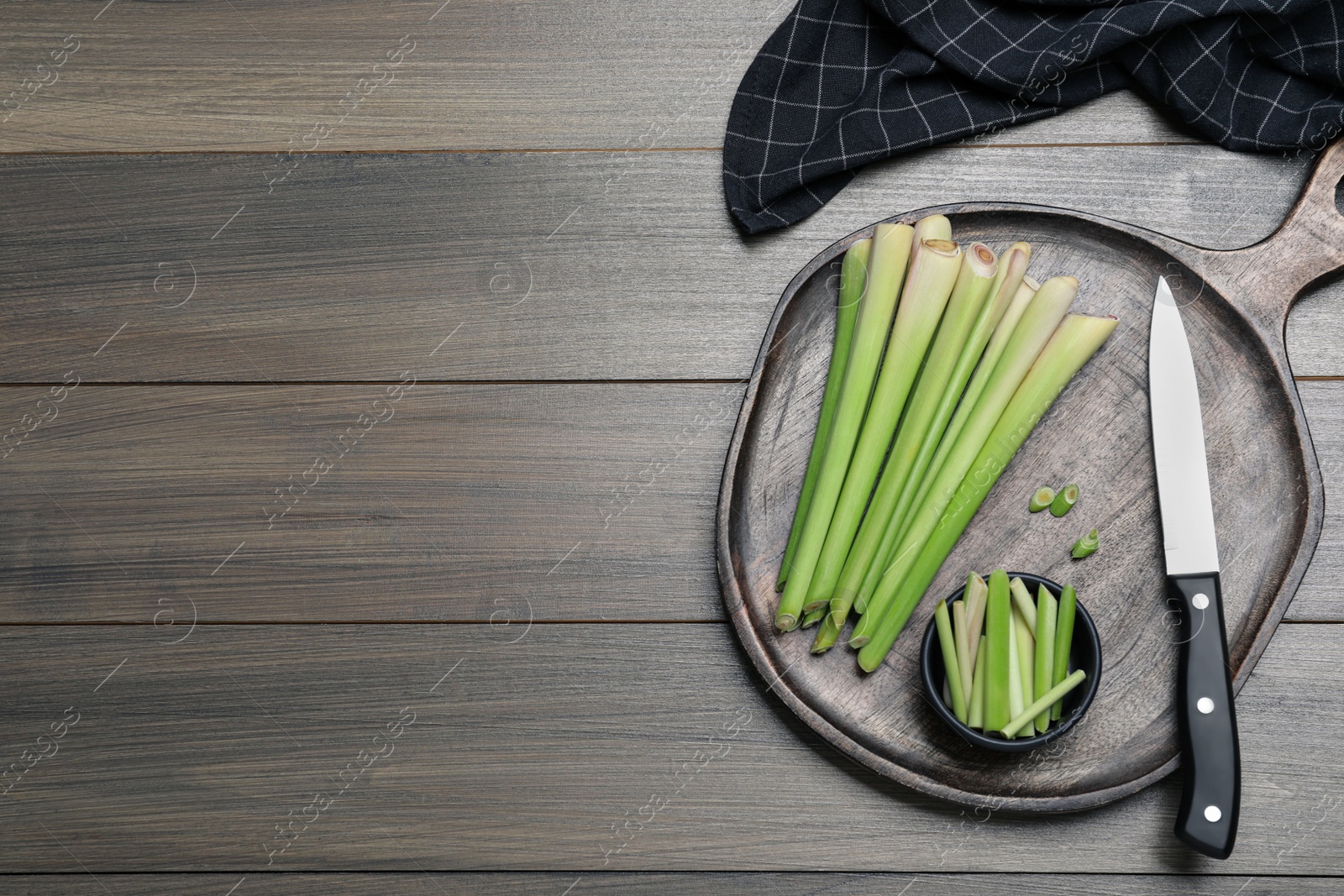 Photo of Fresh lemongrass, knife and cutting board on wooden table, flat lay. Space for text