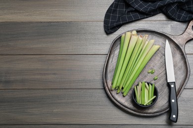 Photo of Fresh lemongrass, knife and cutting board on wooden table, flat lay. Space for text