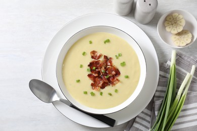 Photo of Tasty potato soup with bacon in bowl served on white wooden table, flat lay