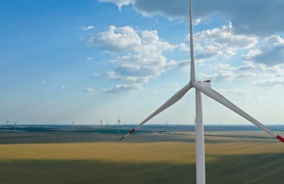 Photo of Modern windmill in field, space for text. Energy efficiency