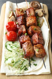 Delicious shish kebabs with vegetables and lavash on table, closeup
