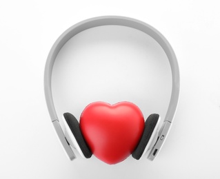 Photo of Headphones and red heart on white background, top view