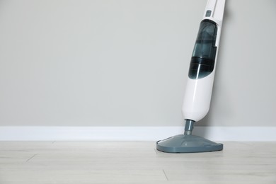 One modern steam mop on floor near grey wall, space for text