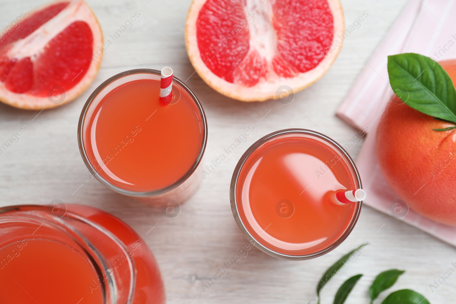 Photo of Tasty freshly made grapefruit juice and fruits on white wooden table, flat lay