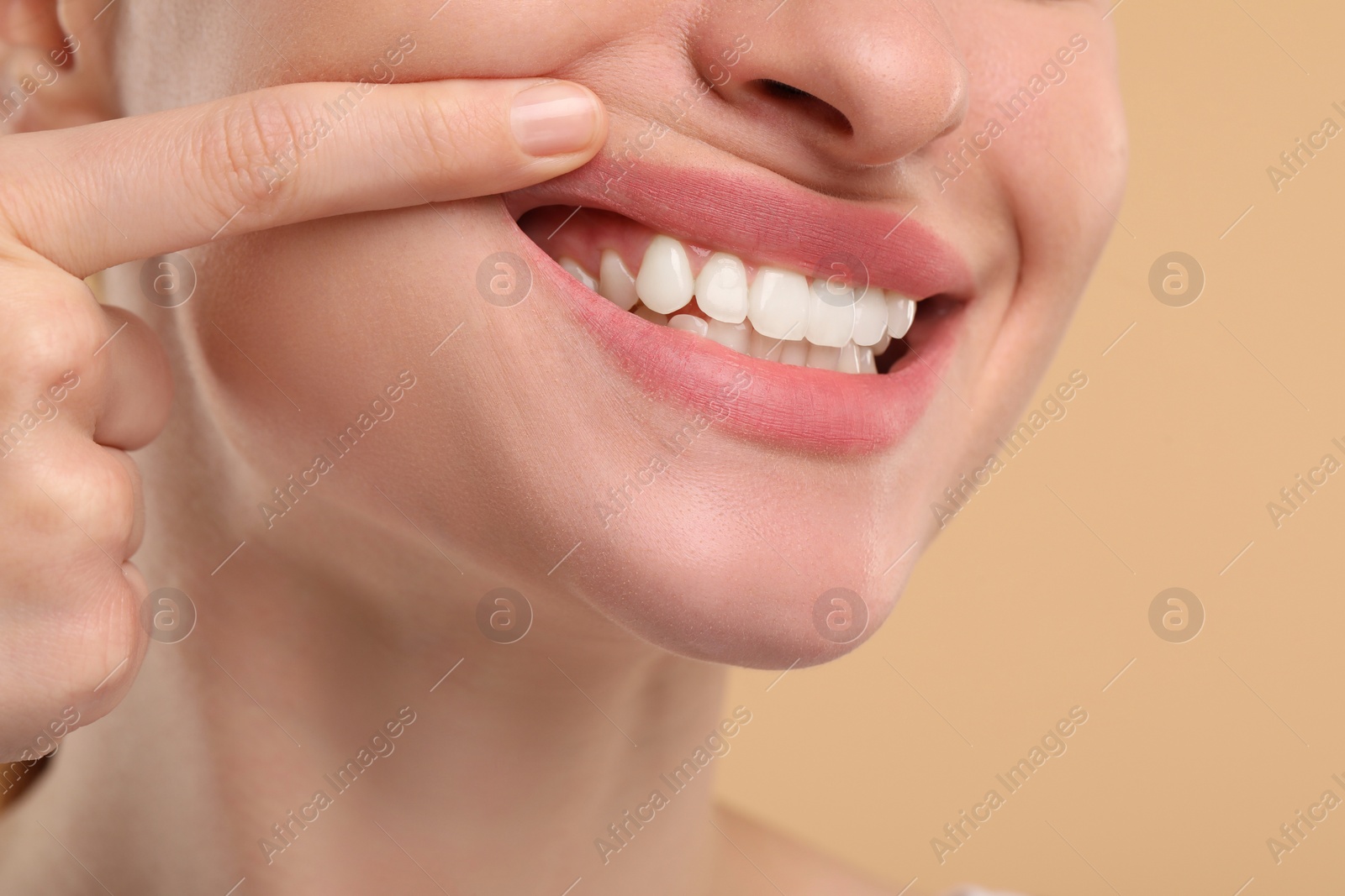 Photo of Woman showing her clean teeth on beige background, closeup