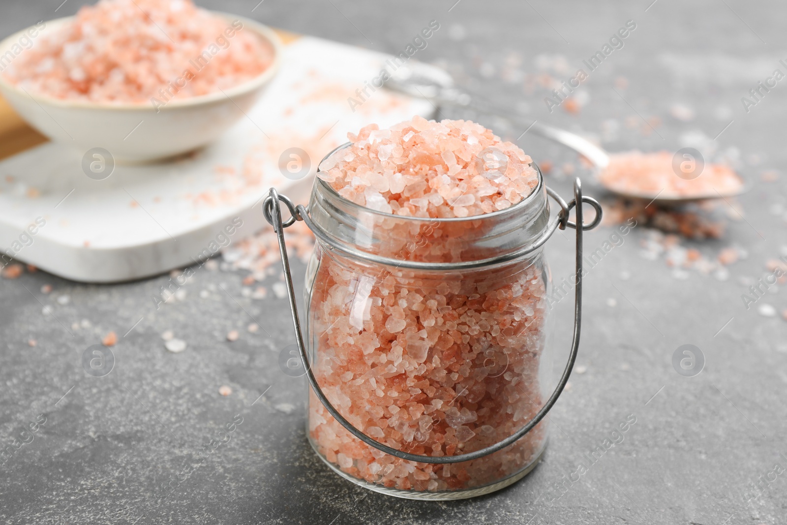 Photo of Pink himalayan salt in glass jar on grey table